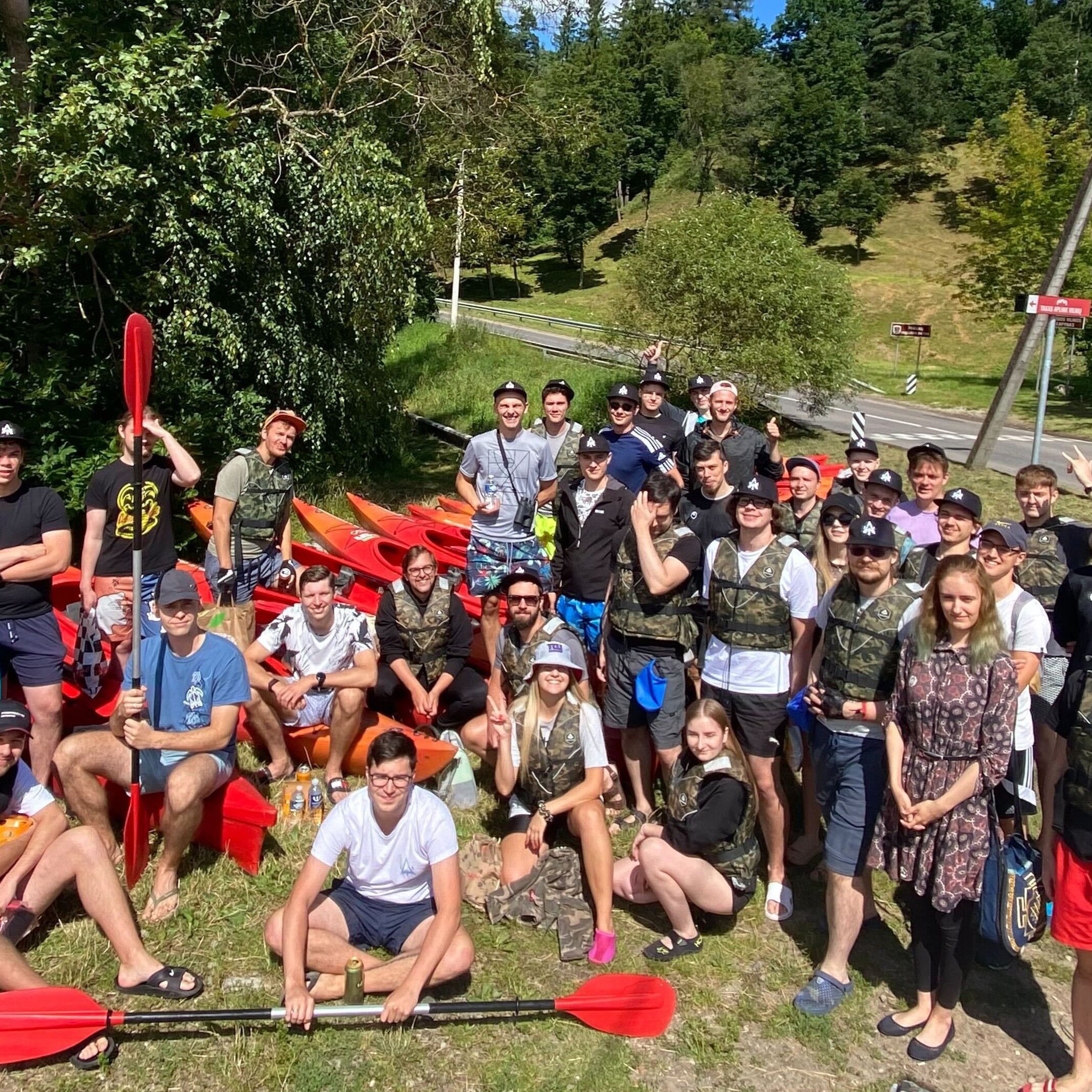 Eldorado team members posing for a group picture with red kayaks and paddles on a sunny day outdoors.